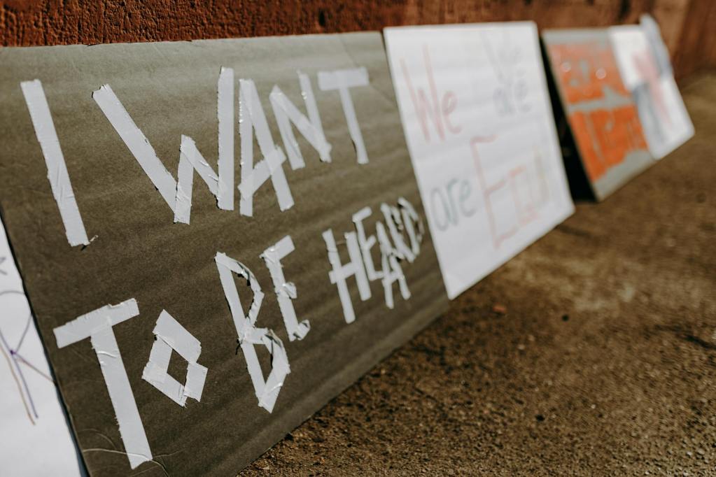 Close-up of a protest sign on the ground reading “I Want to Be Heard”
